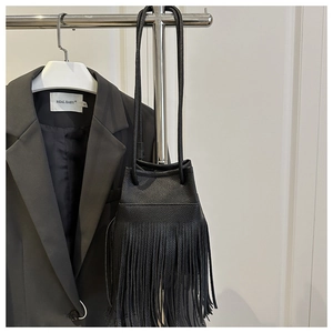 Detail of premium black pebbled leather bucket bag with long fringe and drawstring closure