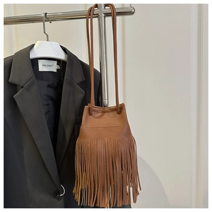 Close-up of brown pebbled leather bucket bag with long fringe tassels and drawstring
