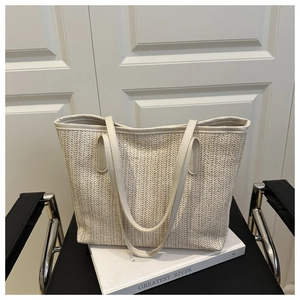 Close-up of cream woven tote bag featuring herringbone pattern and leather straps