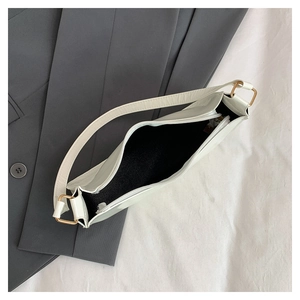 Top view of white minimalist baguette bag showing internal black lining and gold hardware