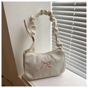 Détail du sac crème avec broderie nœud rose et poignée plissée de style scrunchie