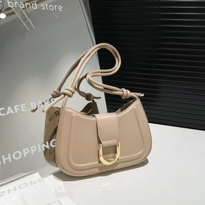 Modern apricot half-moon saddle bag with golden U-shaped buckle on a minimalist platform
