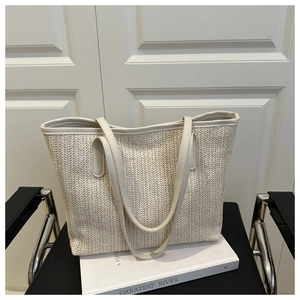 Close-up of beige woven tote bag with V-pattern texture and long leather handles
