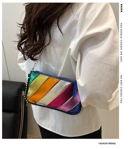 Close-up of rainbow metallic striped chain bag with studs on a white puffy sleeve outfit