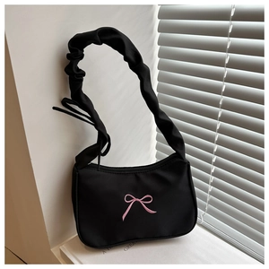 Gros plan du sac noir à poignée froncée avec nœud brodé rose et fermeture éclair