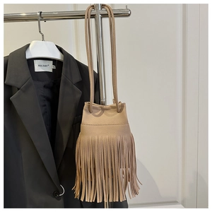 Detail of beige bucket bag with long tassels and lychee texture grain leather