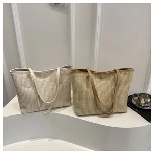 Détail de sacs cabas en paille tressée avec poignées en similicuir en beige et kaki