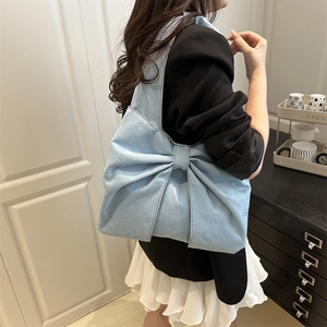 Light blue denim shoulder bag featuring a large decorative bow and minimalist design