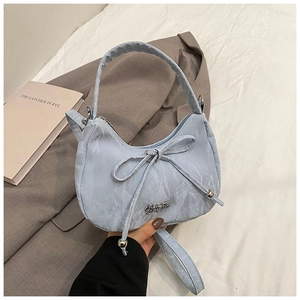 Detail shot of blue crescent bag with bow decoration and metallic silver logo