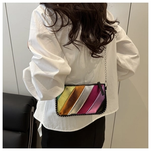 Detail of metallic rainbow striped crossbody bag with chain strap on a white shirt model