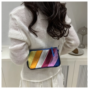 Rainbow striped metallic crossbody bag shown on a model in a stylish home setting
