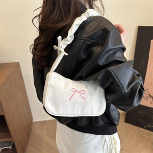 Sac à bandoulière blanc plissé avec broderie nœud rose porté par un mannequin en veste cuir