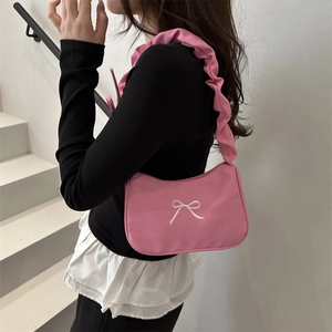 Sac à bandoulière rose avec broderie nœud et bandoulière à volants porté par un modèle