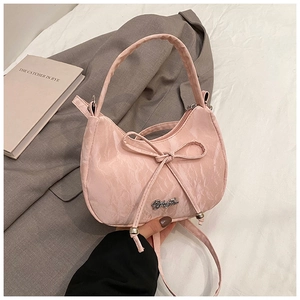 Detail of pink bow handbag with pleated texture and silver zipper on white bedding