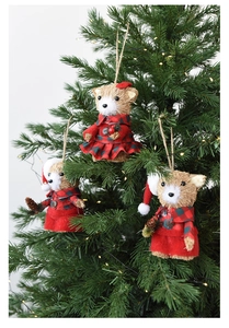 Three straw Christmas bear ornaments hanging on a tree with festive mini pine cones