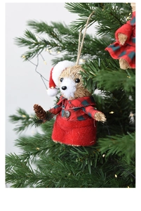 Detail of Christmas fox plush ornament with red plaid dress hanging on a festive tree