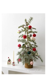 Felt wool balls in assorted colors hanging as festive ornaments on a Christmas tree