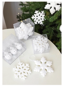 Detalle de adornos navideños de copo de nieve y pájaro blanco en empaque transparente