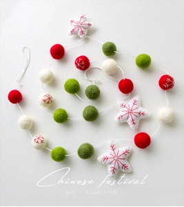 Detail of wool felt garland with red green balls and snowflake embroidered stars
