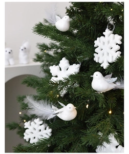 Pájaro de plumas blancas y copo de nieve brillante colgados en un árbol de Navidad decorado