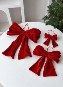 Three red velvet Christmas bows in various sizes on a table for festive decoration