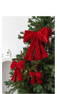 Red velvet Christmas tree bow ornaments in various sizes hanging on a festive tree