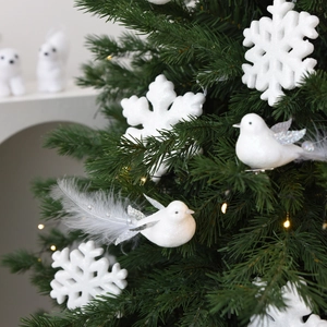 Pájaro decorativo blanco con plumas y purpurina plateada en árbol de Navidad con copos