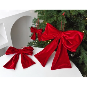 Red velvet Christmas bows in various sizes hanging on a decorated tree with warm lights