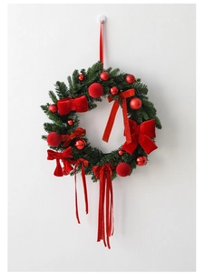 Close-up of a green pine wreath with red matte and glossy balls and velvet bow