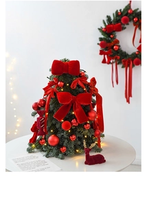 Close-up of mini Christmas tree with red bows, LED lights, and a velvet deer decor
