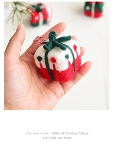 Close-up of handmade wool felt Christmas gift box ornament with a red and white rope hanger
