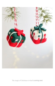 Close-up of wool felt Christmas gift box ornaments hanging with warm festive bokeh lights