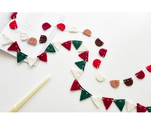 Detail of festive wool felt bunting banner with red and green flags on white background