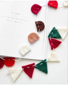 Close-up of colorful felt Christmas bunting featuring red and green flags with white stitching