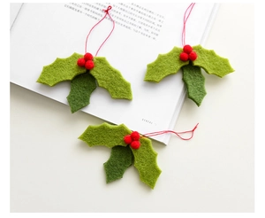 Close-up of wool felt holly leaves and red berry ornaments on a magazine background