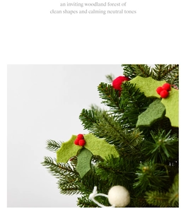 Close-up of wool felt holly leaves and red berries on a green pine needle Christmas tree