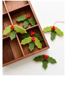 Close-up of wool felt holly leaves with red berry ornaments and red hanging strings