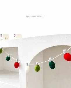 Detail of wool felt festive light-shaped pendants in red and green on a white string