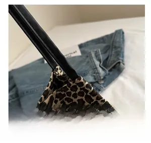 Dettaglio della borsa tote leopardata con manici in pelle nera e cuciture rifinite
