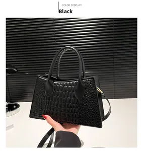 Detail of black crocodile texture handbag with twin handles and crossbody strap
