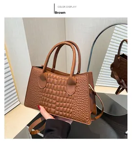 Detail of a brown textured faux crocodile leather handbag with elegant top handles