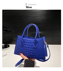 Detail of blue crocodile pattern leather handbag with handles and detachable strap