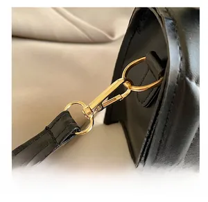 Detail shot of the golden metal hook and D-ring on black leather crossbody bag