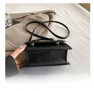 Detailed bottom view of black leather crossbody bag showing durable base and gold hardware