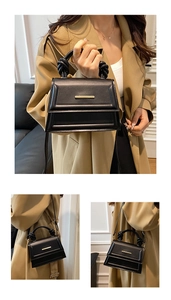 Detail of black leather handbag featuring gold buckle and twisted rope handle design
