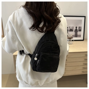 Detailed back view of a black pleated crossbody chest bag with multi-layer silver zippers