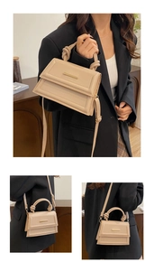 Detail of beige structured handbag with knot handle and gold bar closure