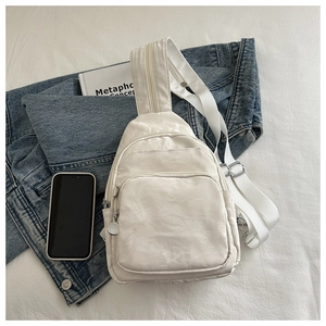 Detail view of cream-white sling bag with natural textured fabric and adjustable strap