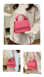 Detail of pink PU leather bag with knotted handle and elegant gold metal trim