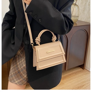 Detail of beige PU leather crossbody bag with knot handle and gold metal clasp